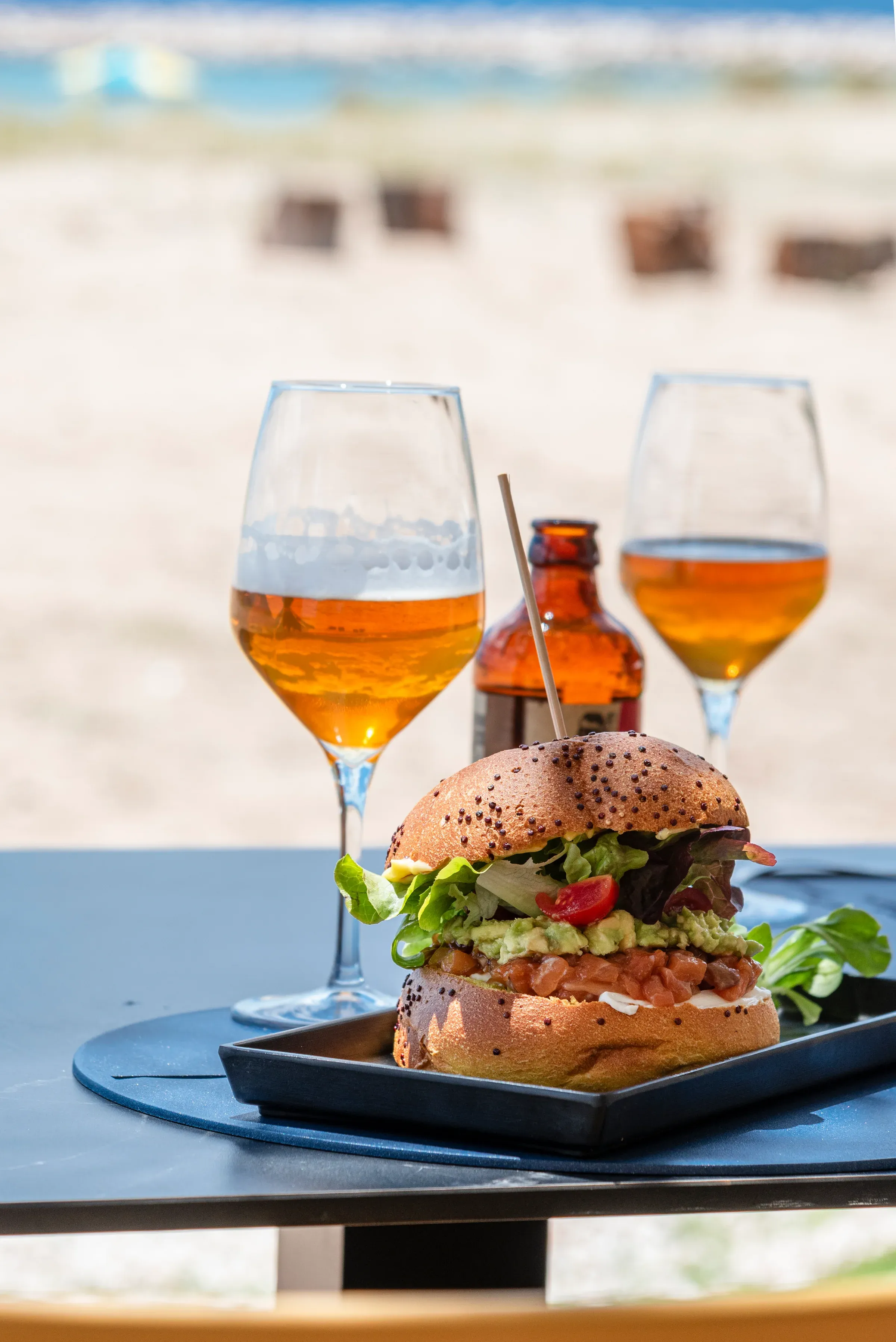 Panino del bistrot servito al tavolo con bicchieri e mare sullo sfondo